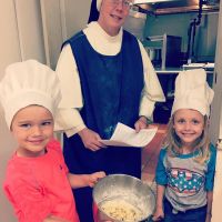 girls wearing chef hats helping with cooking