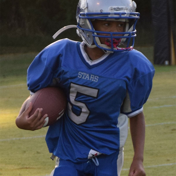 A student dressed in football pads on the field